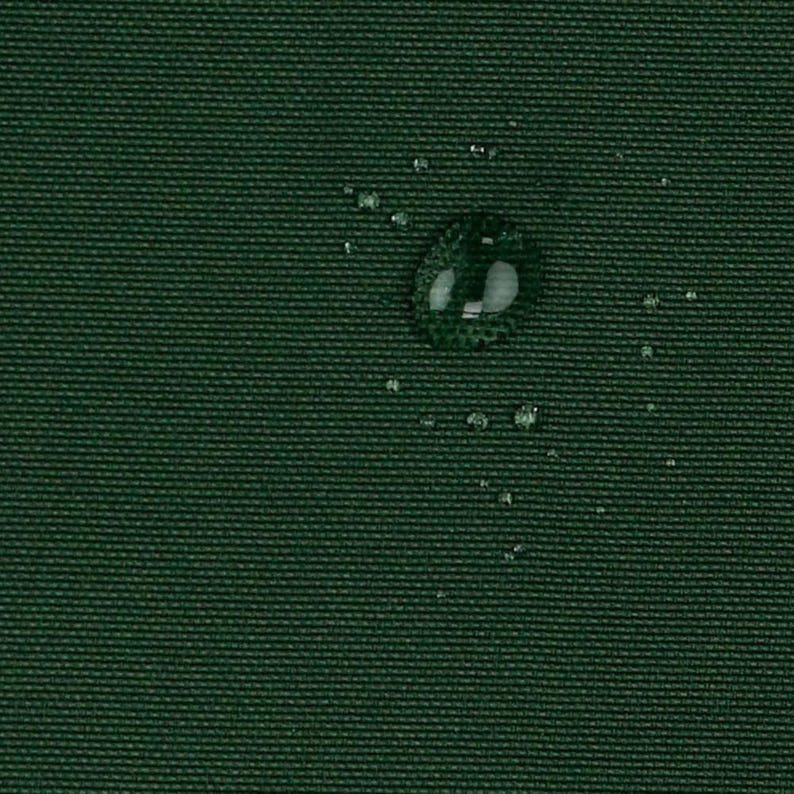 May include: A dark green fabric with a visible woven texture. Several clear water droplets are scattered across the surface, with one larger droplet prominently displayed near the center, reflecting light on the dark material.