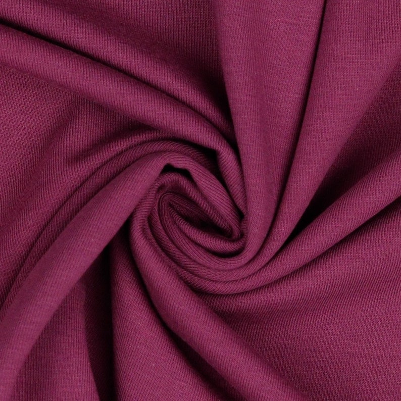 May include: Close-up of a deep burgundy ribbed fabric. The fabric is soft and has a subtle texture.