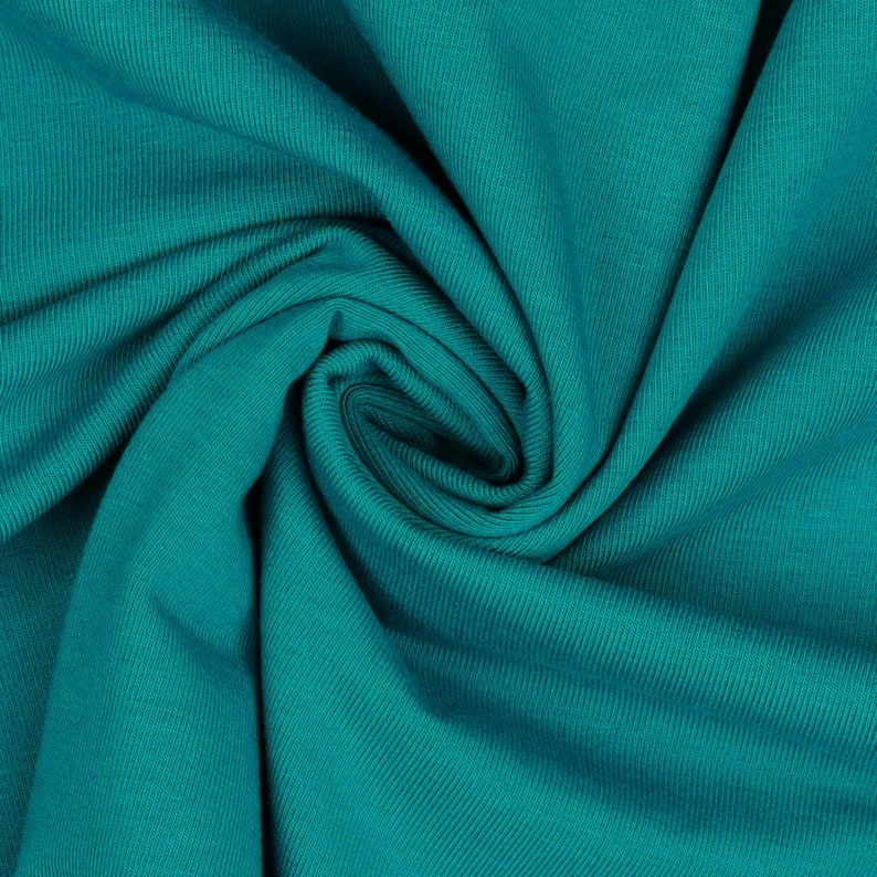 May include: Close-up of teal blue ribbed fabric, showing the texture and folds of the material.