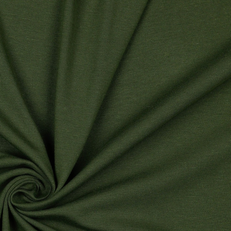 May include: Close-up of a dark green fabric with a ribbed texture. The fabric is folded and draped, showing its soft and flexible nature.