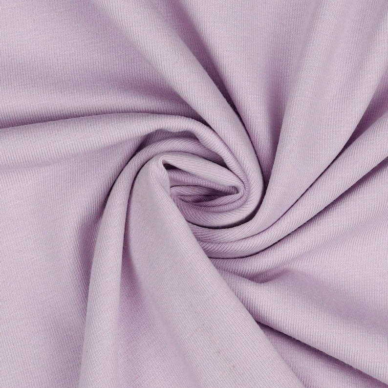 May include: A close-up of a soft, light purple ribbed fabric. The fabric is folded and twisted, showing its texture.