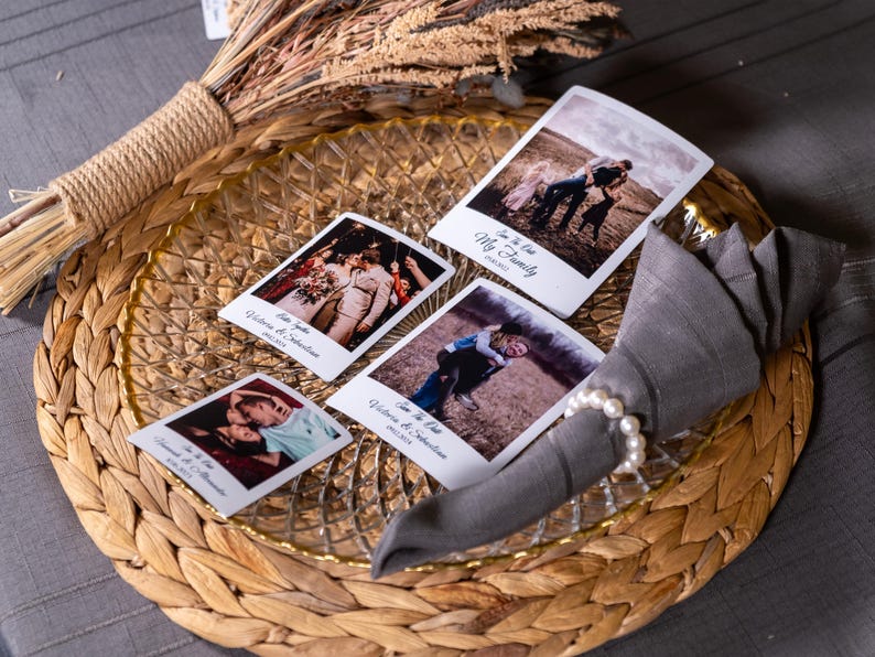 K&ouml;nnte beinhalten: Vier Sofortbild-Fotos mit wei&szlig;en R&auml;ndern und Text auf einem geflochtenen Platzdeckchen mit einem Glasteller und einer grauen Serviette mit einem Perlenring. Die Fotos zeigen ein Paar, eine Familie und zwei Kinder.