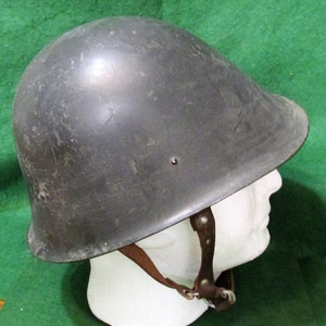 May include: A black military helmet with a leather strap. The helmet has a rounded shape and a smooth surface.