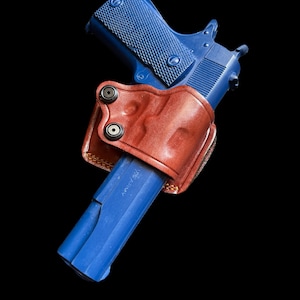 May include: A blue handgun with a brown leather holster. The holster has three metal snaps.