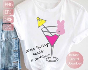 May include: White t-shirt with a pink cocktail glass with a yellow umbrella and a pink bunny on the rim. The text "some bunny needs a cocktail" is written below the glass.
