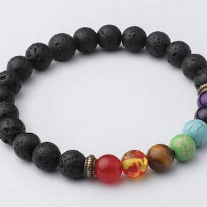 May include: A black lava stone bracelet with a mix of colorful gemstone beads. The bracelet features a series of black, porous lava beads and a selection of vibrant, round gemstones in various colors, including red, yellow, brown, green, blue, and purple.