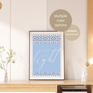 Könnte beinhalten: Ein hellblauer, druckbarer Wandkunstdruck mit einem blauen und weißen Muster an der Kante. Der Druck zeigt das Wort "light" in weißer, kursiv geschriebener Schrift und ein Zitat über Licht. Der Druck wird auf einem Unterhaltungszentrum aus Holz mit einer weißen Schublade gezeigt.