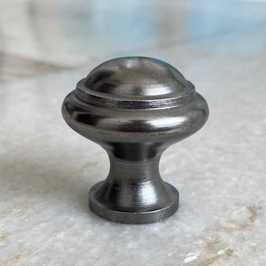 May include: A silver metal cabinet knob with a rounded top and a decorative ring around the base.