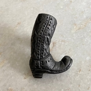 以下が含まれることがあります： 黒い鋳鉄製のブーツ型のドアノブまたはプル。ブーツは詳細なデザインと尖ったつま先をしています。