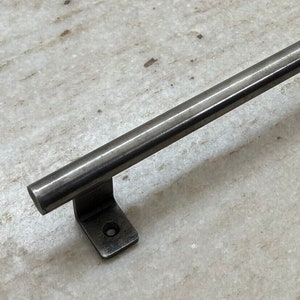 May include: A silver metal door pull handle with rounded edges and a rectangular base. The handle is approximately 12 inches long.