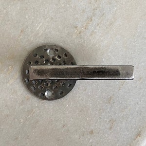 May include: A silver door handle with a square pattern on the base and a long, rectangular lever.