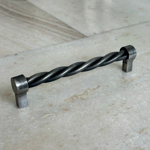 以下が含まれることがあります： ダークグレーの仕上げのツイストメタルキャビネットプル。プルは約10cmの長さです。