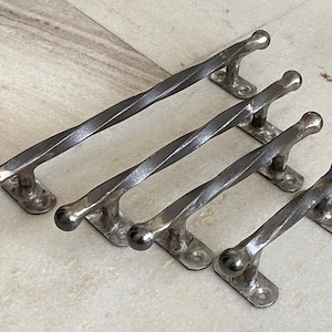 May include: Four twisted metal handles with rounded ends. The handles are silver in color and have a rustic finish.