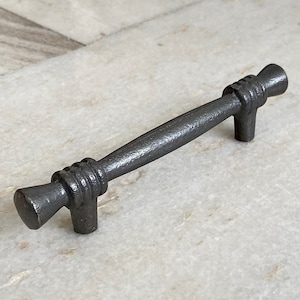 May include: A black metal cabinet pull with a rounded, textured design. The pull is approximately 4 inches long.