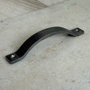 Op de afbeelding: Een zwarte metalen kastdeurknop met een getextureerd oppervlak.