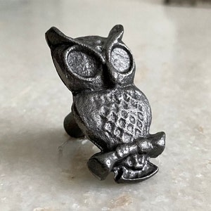 以下が含まれることがあります： 詳細なデザインが施された灰色の金属製のフクロウの置物。フクロウは枝に止まっており、翼を広げています。