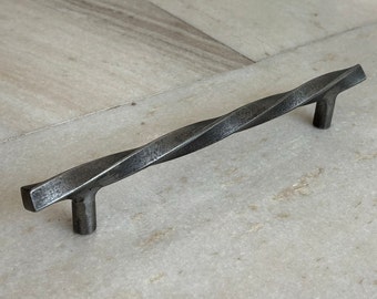 May include: A twisted metal cabinet pull with a dark gray finish.