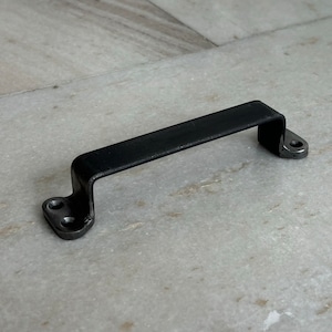 Könnte beinhalten: Schwarzer Türgriff aus Metall mit zwei Schraubenlöchern auf jeder Seite.