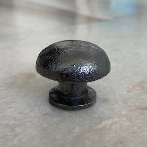 May include: A black cast iron mushroom-shaped cabinet knob.