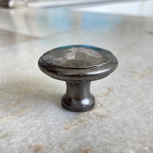 May include: A silver metal cabinet knob with a hammered finish. The knob has a round top and a short, cylindrical base.