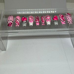 May include: Set of ten pink and white false nails with various designs including hearts, polka dots, and the words "Girl Power".
