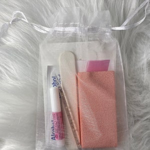 May include: A white organza bag filled with nail care supplies. The bag contains a nail file, a pink nail buffer, and a small bottle of alcohol.