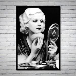 May include: A black and white photo of a woman with blonde hair applying makeup while looking in a vanity mirror.
