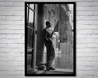 May include: Black and white framed print of a man in a suit holding an umbrella, leaning against a column. The image is a classic, vintage style, with a rainy street scene in the background.