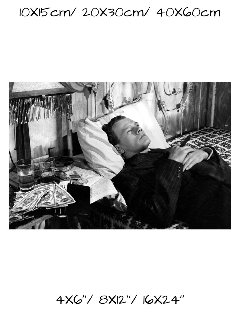 K&ouml;nnte beinhalten: Schwarzwei&szlig;foto eines Mannes, der im Bett liegt. Er tr&auml;gt einen Anzug und hat die H&auml;nde auf der Brust gefaltet. Auf einem Tisch neben dem Bett stehen Gl&auml;ser und Geld.