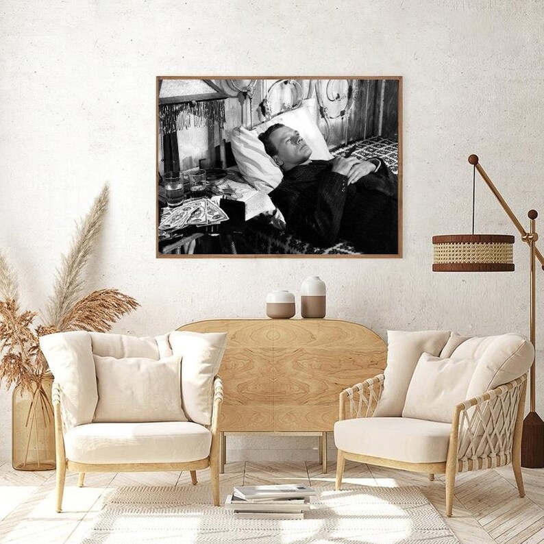 K&ouml;nnte beinhalten: Schwarzwei&szlig;foto eines Mannes, der im Bett liegt. Der Mann tr&auml;gt einen Anzug und hat seine H&auml;nde auf der Brust gefaltet. Das Bett ist mit einem wei&szlig;en Laken und einem Kissen bezogen. Auf einem Tisch neben dem Bett steht ein Glas Fl&uuml;ssigkeit und eine Schachtel Zigaretten.