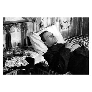 K&ouml;nnte beinhalten: Schwarzwei&szlig;foto eines Mannes, der im Bett liegt. Er tr&auml;gt einen Anzug und hat die H&auml;nde auf der Brust gefaltet. Neben ihm auf dem Nachttisch stehen Gl&auml;ser und Geld. Das Bild ist 60 x 90 cm oder 24 x 36 Zoll gro&szlig;.