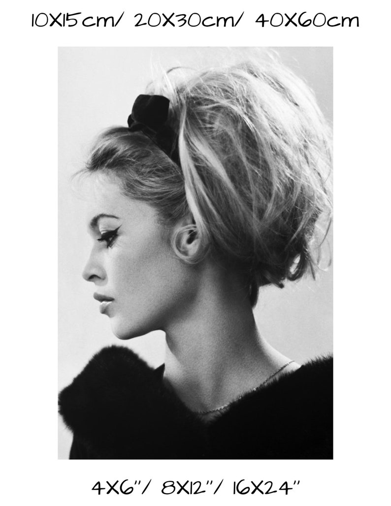 May include: Black and white portrait photograph of a woman with her hair styled in a high bouffant. She is wearing a black fur collar and a thin silver necklace.