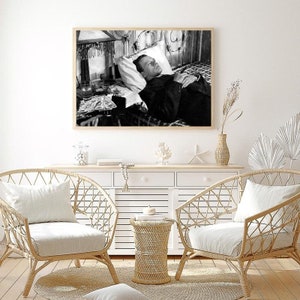 K&ouml;nnte beinhalten: Schwarzwei&szlig;foto eines Mannes, der im Bett liegt und zur Decke schaut. Der Mann tr&auml;gt eine Sakkojacke und eine Krawatte. Neben ihm stehen Gl&auml;ser und ein Tablett auf einem Tisch.