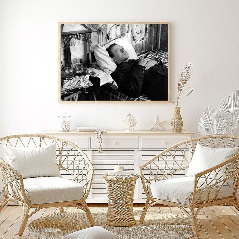 K&ouml;nnte beinhalten: Schwarzwei&szlig;foto eines Mannes, der im Bett liegt und zur Decke schaut. Der Mann tr&auml;gt eine Sakkojacke und eine Krawatte. Neben ihm stehen Gl&auml;ser und ein Tablett auf einem Tisch.