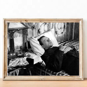 K&ouml;nnte beinhalten: Schwarzwei&szlig;foto eines Mannes, der mit geschlossenen Augen im Bett liegt. Er tr&auml;gt einen Anzug und hat einen ernsten Gesichtsausdruck. Neben ihm steht ein Tisch mit mehreren Gl&auml;sern Fl&uuml;ssigkeit.