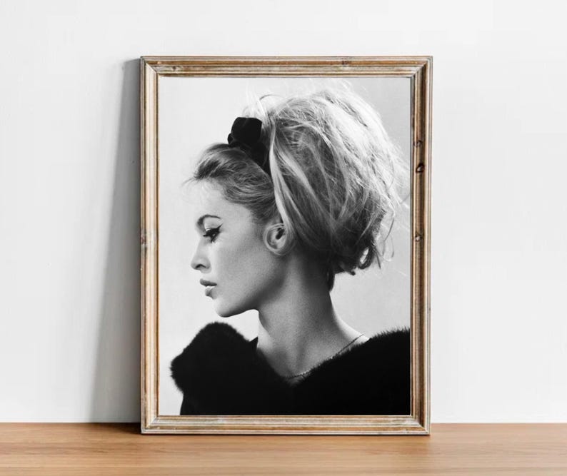May include: Black and white portrait photograph of a woman with her hair styled in a bouffant. She is wearing a black fur collar and a black headband.