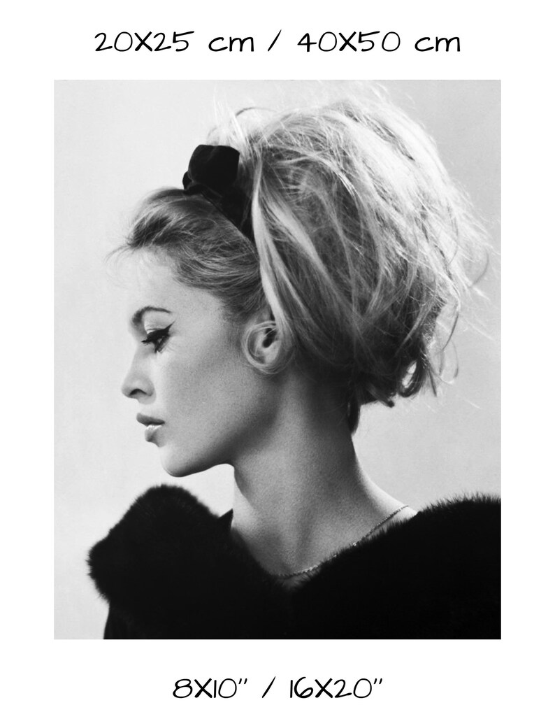 May include: Black and white portrait photograph of a woman with her hair styled in a bouffant. She is wearing a black fur collar and a thin necklace.