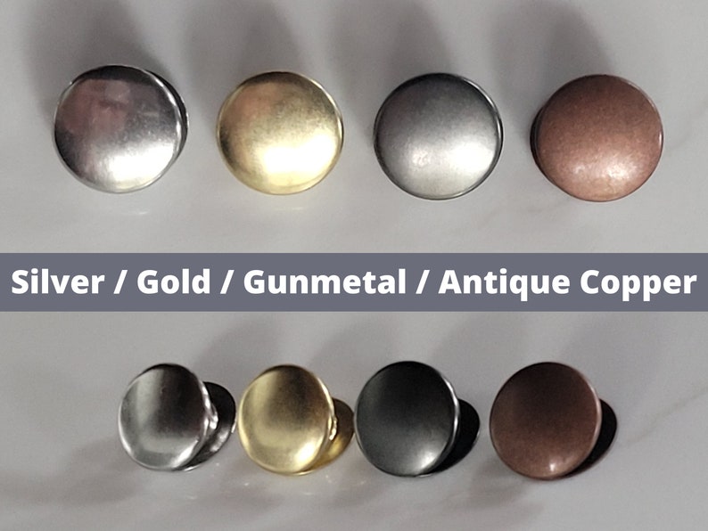 May include: Four round metal buttons in different finishes: silver, gold, gunmetal, and antique copper. The buttons are arranged in two rows of two.