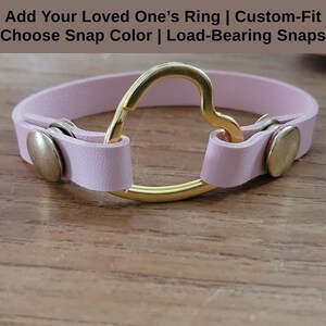 May include: A pink leather bracelet with a gold heart-shaped ring and two gold snaps.  Add Your Loved One's Ring | Custom-Fit Choose Snap Color | Load-Bearing Snaps