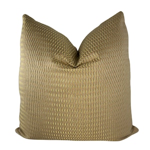 May include: A decorative pillow with a textured, woven pattern in shades of gold and tan. The pillow has a soft, plush appearance and is designed for home decor. The fabric has a subtle sheen, adding to its luxurious look.