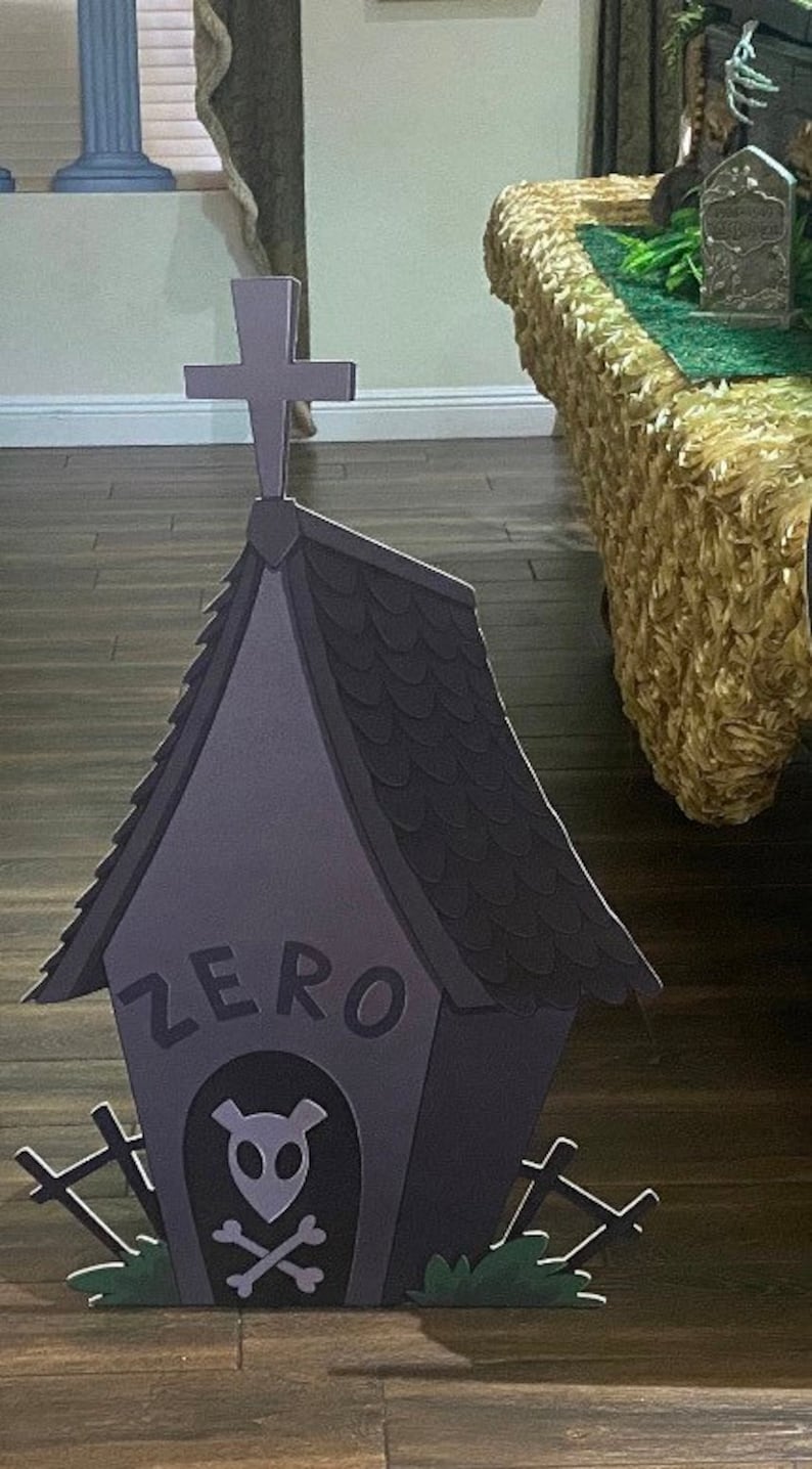 May include: A black and grey cardboard cutout of a dog house with a cross on top. The dog house has a sign that says "ZERO" and a skull and crossbones inside. The dog house is on a wooden floor.