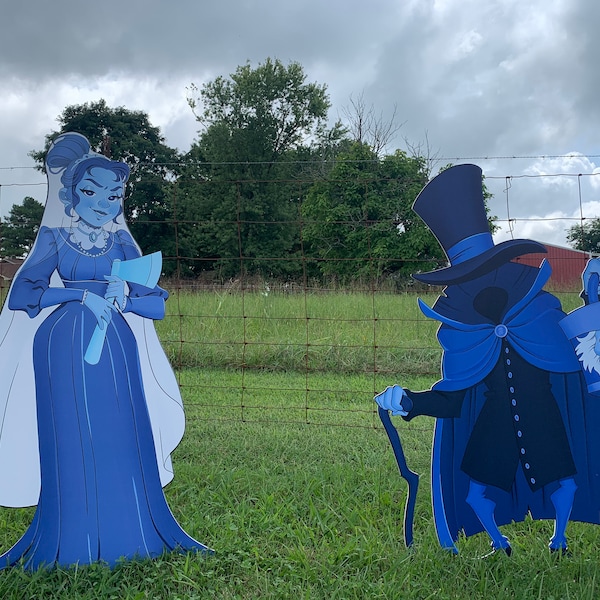 May include: Two blue cardboard cutouts of spooky characters. A female ghost bride with a white veil and an axe, and a male ghost with a top hat and a bucket.