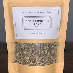 May include: A brown paper pouch with a white label that reads "PETUNIA'S HERBAL CO. RED RASPBERRY LEAF 1 OZ 100% ORGANIC". The pouch contains dried red raspberry leaves.