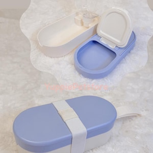 K&ouml;nnte beinhalten: Ein Reise-Set f&uuml;r Haustiere mit einem hellblauen und wei&szlig;en Futterbeh&auml;lter mit wei&szlig;em Riemen, einer blau-wei&szlig;en Wasserschale mit wei&szlig;em Deckel und einer transparenten Wasserflasche. Ideal f&uuml;r Reisen mit Haustieren.