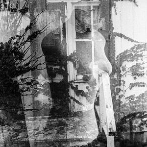 May include: A black and white photograph of a house with a window and a porch. The house is covered in vines and the image is slightly blurred.
