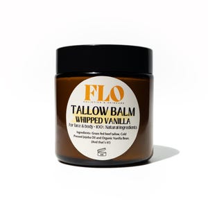 Op de afbeelding: Een bruine pot met een zwart deksel, met het opschrift "TALLOW BALM WHIPPED VANILLA" met het FLO Holistic & Skincare logo. De tekst geeft aan dat het voor gezicht en lichaam is, gemaakt met natuurlijke ingredi&euml;nten.