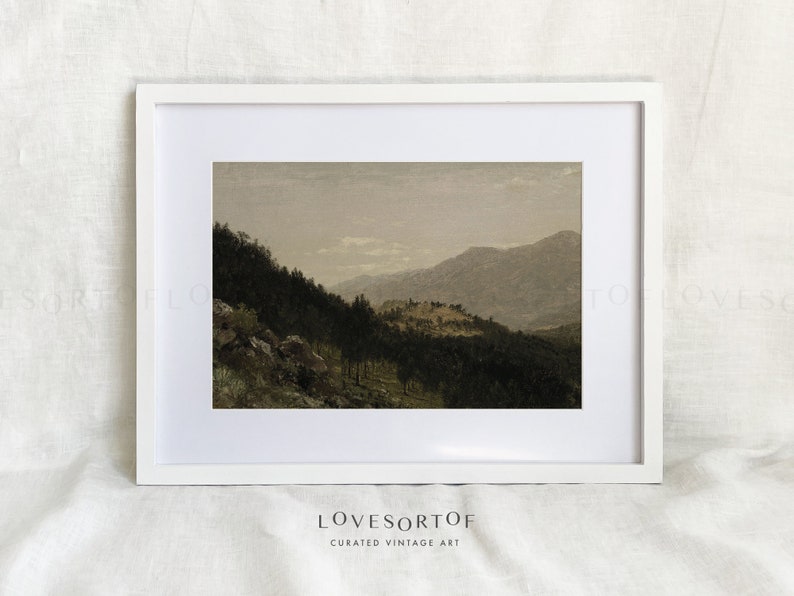 K&ouml;nnte beinhalten: Ein gerahmtes Vintage-Landschaftsfoto mit einer nebelverhangenen Bergkette und einem Wald im Vordergrund. Das Foto ist in Braun-, Gr&uuml;n- und Blaut&ouml;nen gehalten.