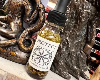 May include: A clear glass bottle with a black dropper filled with a yellow liquid and herbs. The label reads "PROTECT" with a white background and a black symbol. The website "magickamulet.com" is also printed on the label. The bottle is displayed in front of a bronze statue.