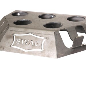 May include: A silver metal stand with six circular cutouts and the word "SWAG" cut out in the center. The stand has three tabs on the side.