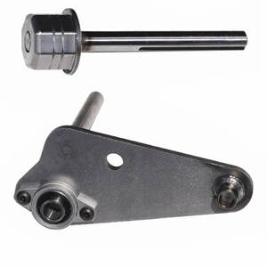 May include: Two metal machine parts are displayed against a white background. The top part is a cylindrical piece with a shaft. The bottom part is a flat, gray metal piece with a bearing and a cylindrical post.